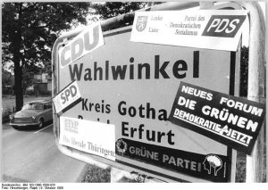 Ortsschild beklebt mit Stickern der bei der Bundestagswahl 1990 zur Wahl stehenden Parteien